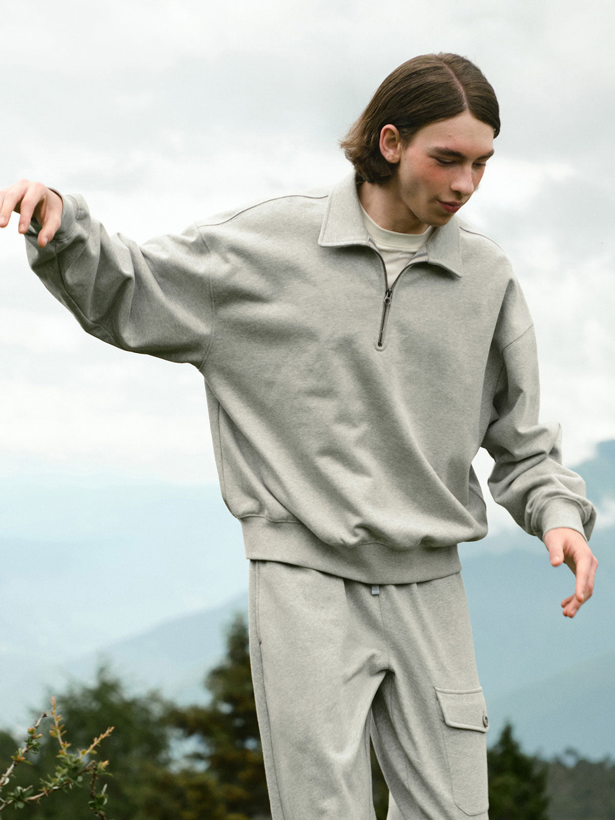 詳細画像: ハーフジップディテールとスタンドカラー部分のクローズアップ。しっかりとした手触りと滑らかな表面感を持つ高品質コットンポリエステル混紡素材のディテールにフォーカス。
モデル画像: モデルがハーフジップ スタンドカラー スウェットとデニムを合わせ、クラシックなアメカジスタイルを披露。コーディネートの多様性を強調し、通勤やカジュアルシーンにも適した着こなし。