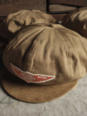 キャップのエラスティックバンド固定デザインと低彩度オレンジ色のバッジのクローズアップ。