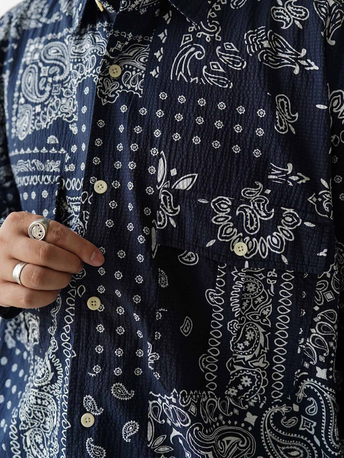 製品画像
ペイズリー柄シアサッカーシャツの正面デザイン。アメリカンバンダナ文化を反映した不規則なプリントパターンと、軽量で通気性の高いシアサッカー生地が特徴
詳細画像
3つのポケットと独特なシワ感を持つシアサッカー生地のディテール。18針/3cmの高密度縫製工法による精密な仕上がりが際立つ