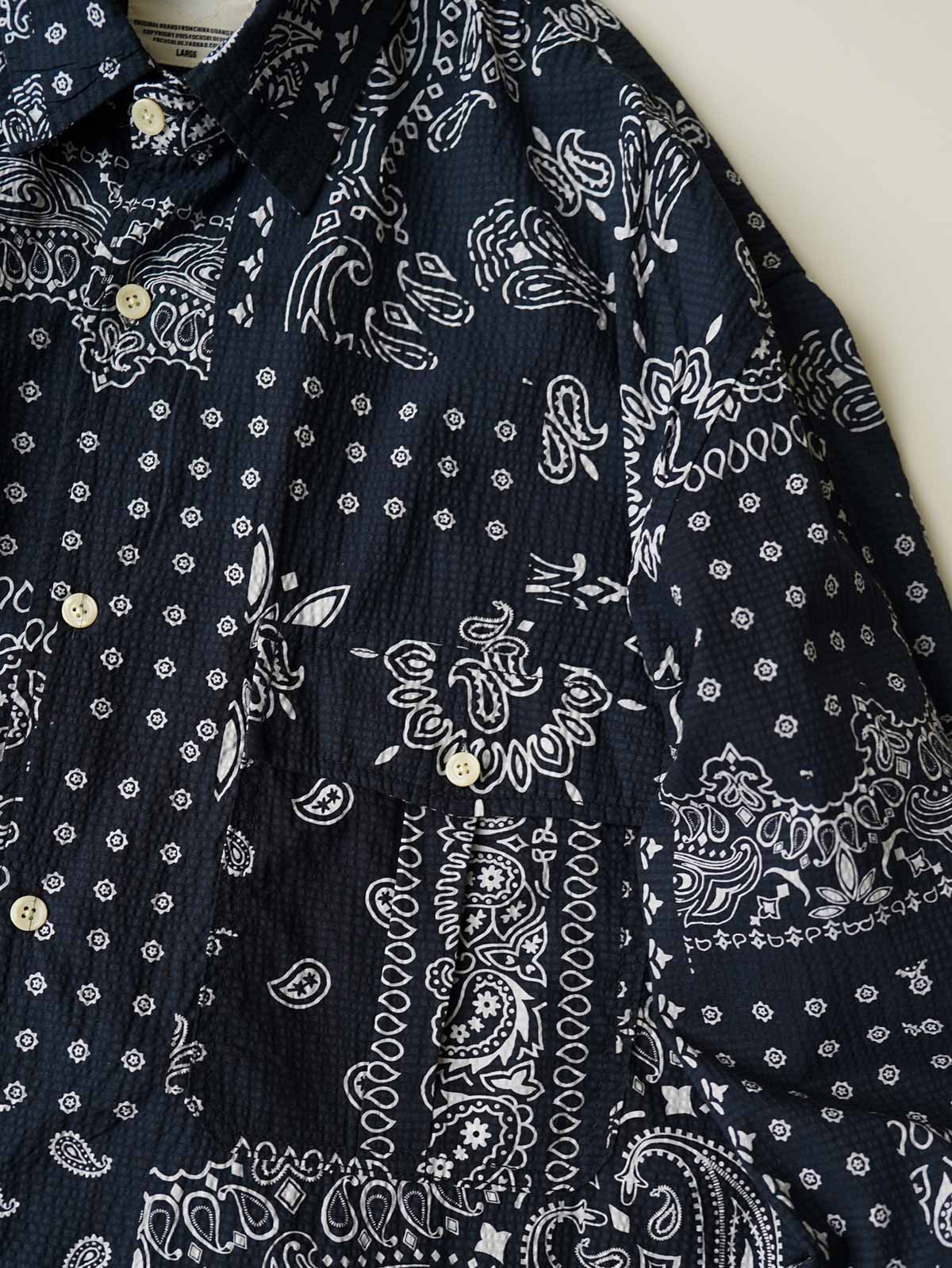 製品画像
ペイズリー柄シアサッカーシャツの正面デザイン。アメリカンバンダナ文化を反映した不規則なプリントパターンと、軽量で通気性の高いシアサッカー生地が特徴
詳細画像
3つのポケットと独特なシワ感を持つシアサッカー生地のディテール。18針/3cmの高密度縫製工法による精密な仕上がりが際立つ