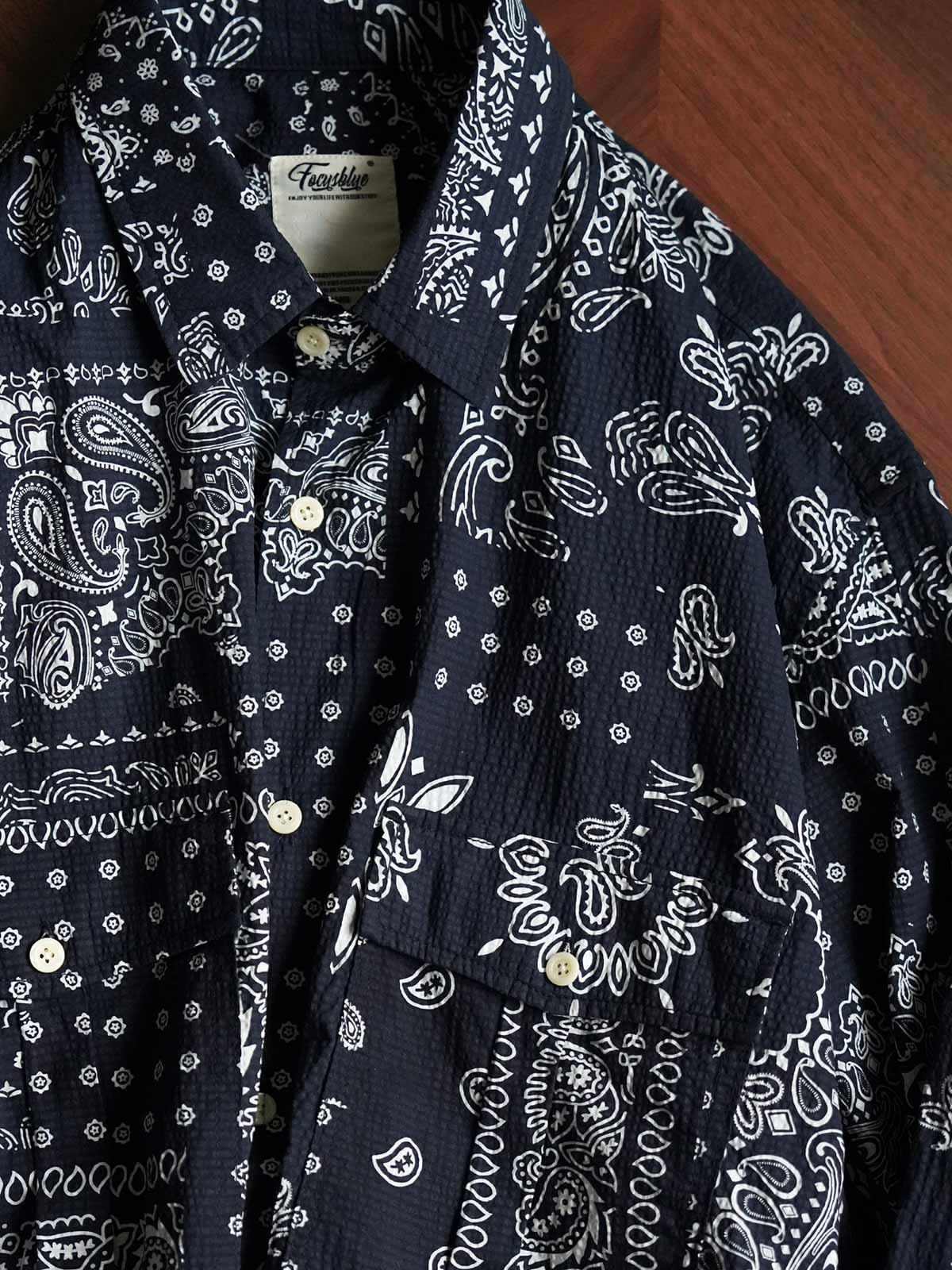 製品画像
ペイズリー柄シアサッカーシャツの正面デザイン。アメリカンバンダナ文化を反映した不規則なプリントパターンと、軽量で通気性の高いシアサッカー生地が特徴
詳細画像
3つのポケットと独特なシワ感を持つシアサッカー生地のディテール。18針/3cmの高密度縫製工法による精密な仕上がりが際立つ