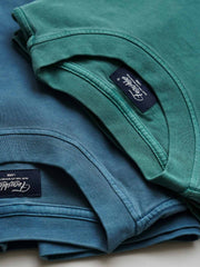 製品画像
ヴィンテージ蝋染めスウェットシャツ正面デザイン。グレイッシュグリーンやデニムブルーなどの植物染料で仕上げた深みのある色合いと、ルーズフィットのシルエットが特徴。日本伝統の蝋染め技法によるユニークな色彩表現が際立つ一着
詳細画像
ネックライン周辺の精密な3cmあたり18針ステッチと、蝋染め加工で生まれる独特な色彩の層次感を特写。二重構造の肩テープとサイドステッチのディテールが、耐久性と快適な着心地を提供する仕上がり