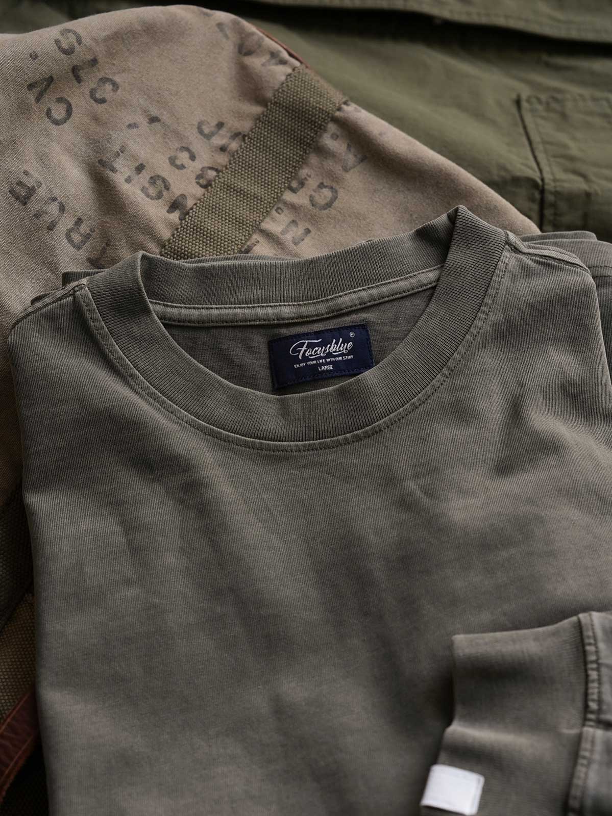 製品画像
ヴィンテージ蝋染めスウェットシャツ正面デザイン。グレイッシュグリーンやデニムブルーなどの植物染料で仕上げた深みのある色合いと、ルーズフィットのシルエットが特徴。日本伝統の蝋染め技法によるユニークな色彩表現が際立つ一着
詳細画像
ネックライン周辺の精密な3cmあたり18針ステッチと、蝋染め加工で生まれる独特な色彩の層次感を特写。二重構造の肩テープとサイドステッチのディテールが、耐久性と快適な着心地を提供する仕上がり