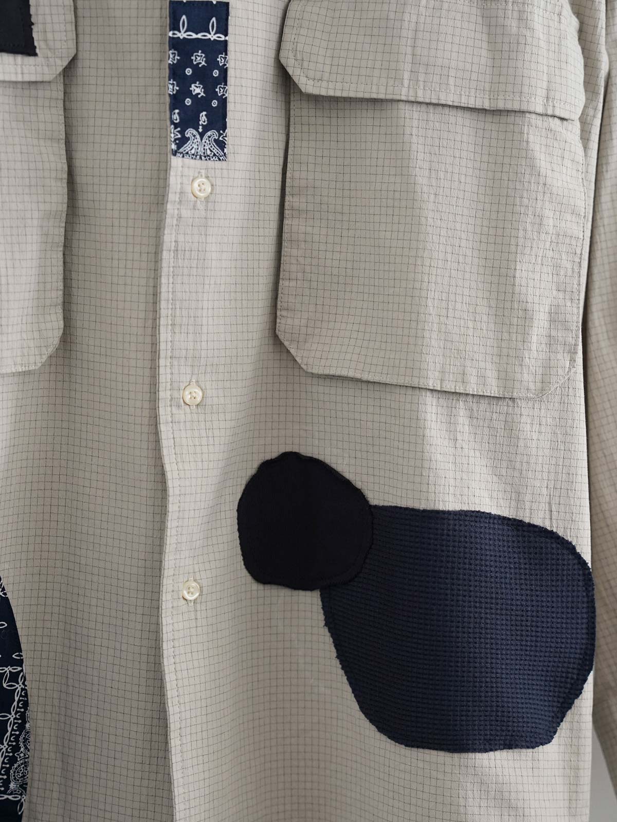 製品画像
ボロパッチワーク ワークシャツ全体デザイン。ペイズリー柄やヴィンテージニット生地を大胆に取り入れた複雑なパッチワークデザインが特徴。チェック柄と無地素材の質感コントラストが際立つルーズフィットのシルエット
詳細画像
ダブルチェストポケットや肩部分の二重構造のディテール、3cmあたり18針の高密度ステッチが丁寧に仕立てられた特写。耐久性と立体感を両立した洗練された仕上がり