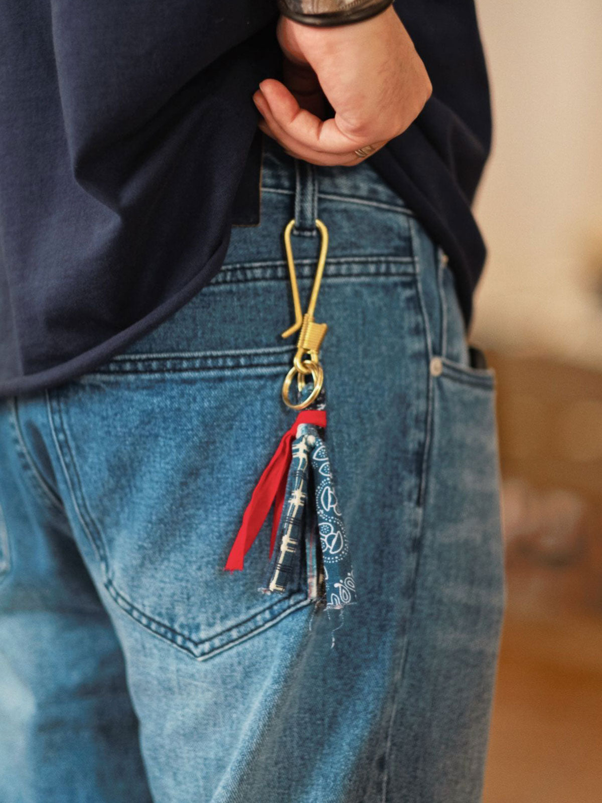詳細画像
「手作りのワイヤー巻き仕上げが施されたブラス製フックと、ペイズリー柄藍染めフリンジのディテールクローズアップ。」
モデル画像
「ペイズリー柄 藍染め キーホルダーをバッグに装着し、日常のヴィンテージ風コーディネートに上品なアクセントをプラス。」