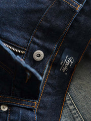 製品画像
「14OZ赤耳デニムパンツ全体イメージ。旧式織機で織られたクラシックな狭幅赤耳デニム生地とインディゴ染めの高品質な仕上がりが特徴。」
詳細画像
「赤耳セルビッジ、インディゴ染め鹿革パッチ、月桂冠モチーフのドーナツボタン、カスタムYKKジッパーなど、クラシックで高級感のあるディテールのクローズアップ。」