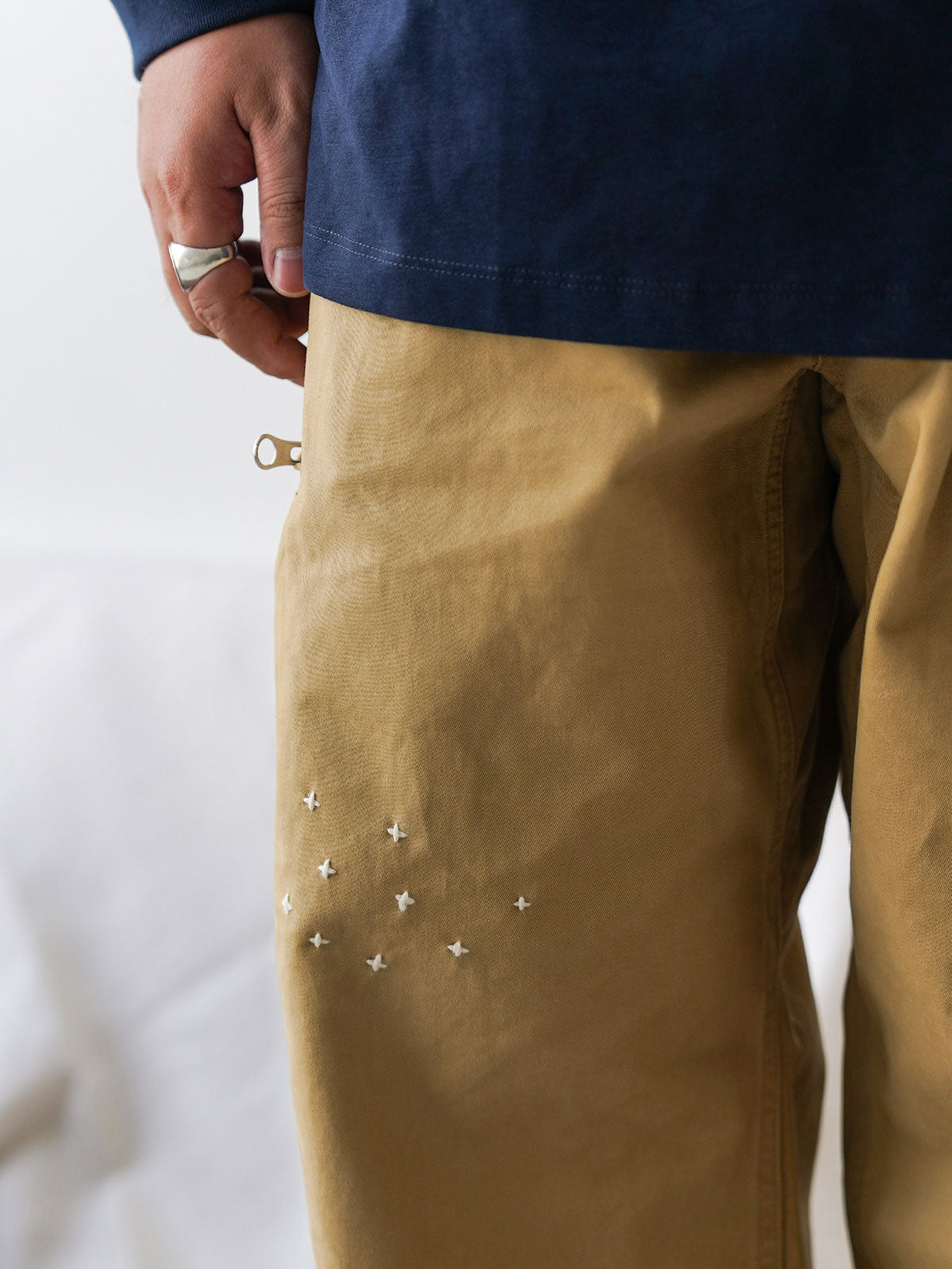 詳細画像
「非対称の刺し子刺繍ディテールと大容量の弧形ポケットをクローズアップ。膝部分の左右異なる刺繍パターンが立体感を強調。」
モデル画像
「カジュアルなトップスと組み合わせたハンド刺し子テーパードパンツ。テーパードシルエットが美しい脚のラインを演出し、モダンで伝統的なスタイルを体現。」