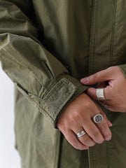 詳細画像
「ハードシェルのような質感を持つチェック柄ファブリックとペイズリー柄コットン裏地、隠しジップポケットや大型スナップボタンのディテールクローズアップ。」
モデル画像
「モデルがヴィンテージ風 通勤用 トレンチジャケットを着用し、大容量ポケットとルーズフィットシルエットで快適さとスタイリッシュさを両立した通勤コーディネート。」