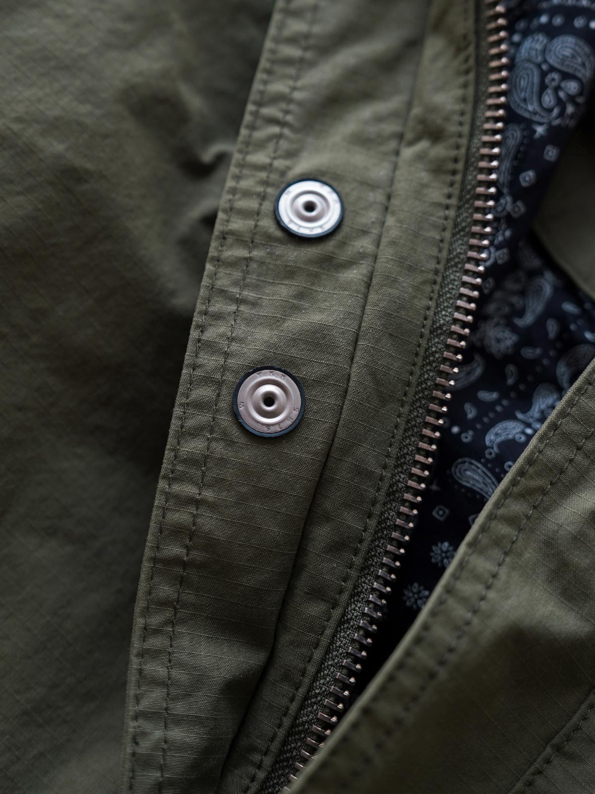 製品画像
「ヴィンテージ風 通勤用 トレンチジャケット全体イメージ。コーティング加工のチェック柄ファブリックとペイズリー柄コットン裏地が特徴の多機能デザイン。」
詳細画像
「ハードシェルのような質感を持つチェック柄ファブリックとペイズリー柄コットン裏地、隠しジップポケットや大型スナップボタンのディテールクローズアップ。」