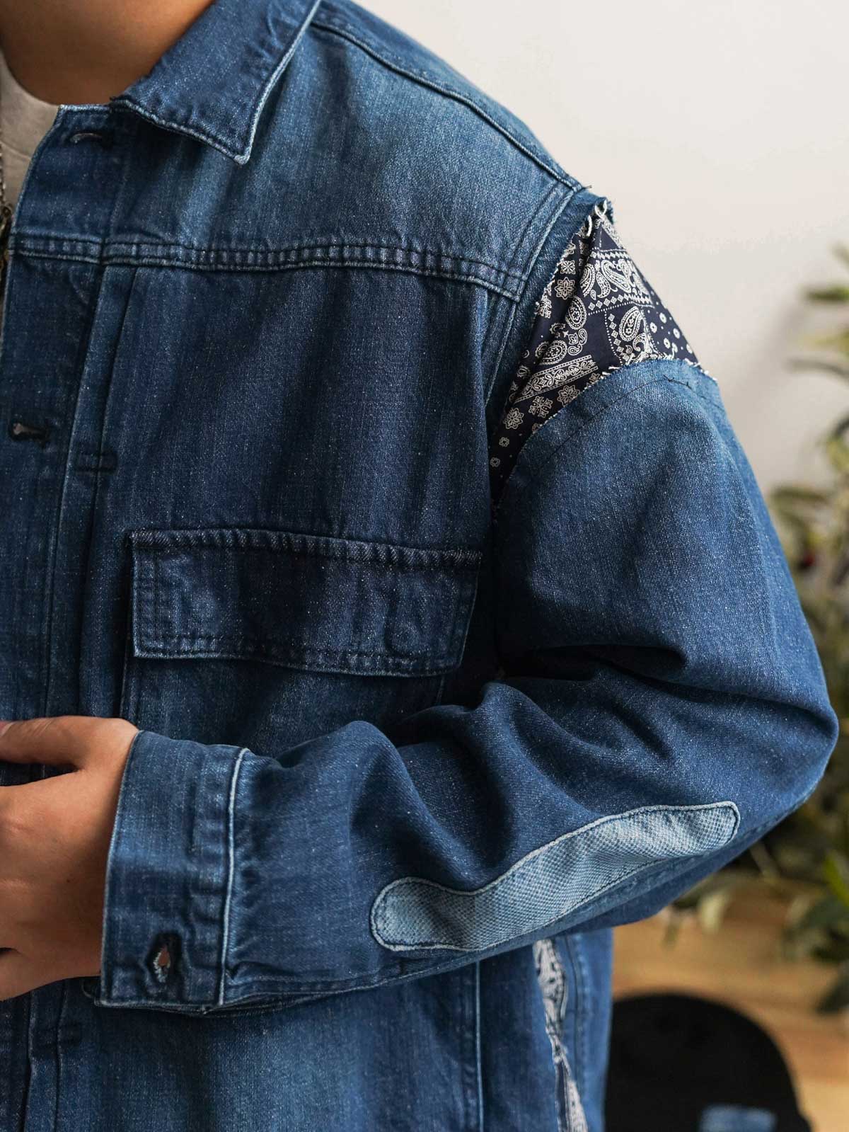 詳細画像
「デコンストラクション パッチワーク ペイズリー柄 デニムジャケットのディテール特写。袖口や裾に施されたペイズリー柄パッチワークのクラフトマンシップや、意図的にずらしたボタンデザインが、ヴィンテージ感と個性を際立たせる。左右非対称の再構築デザインが視覚的なユニークさを演出。」
モデル画像
「デコンストラクション パッチワーク ペイズリー柄 デニムジャケットを着用したモデルが、ワークパンツと組み合わせたレトロなヴィンテージスタイルを披露。オーバーサイズシルエットで自由な着こなしが楽しめるトレンド感あふれるコーディネート。」
