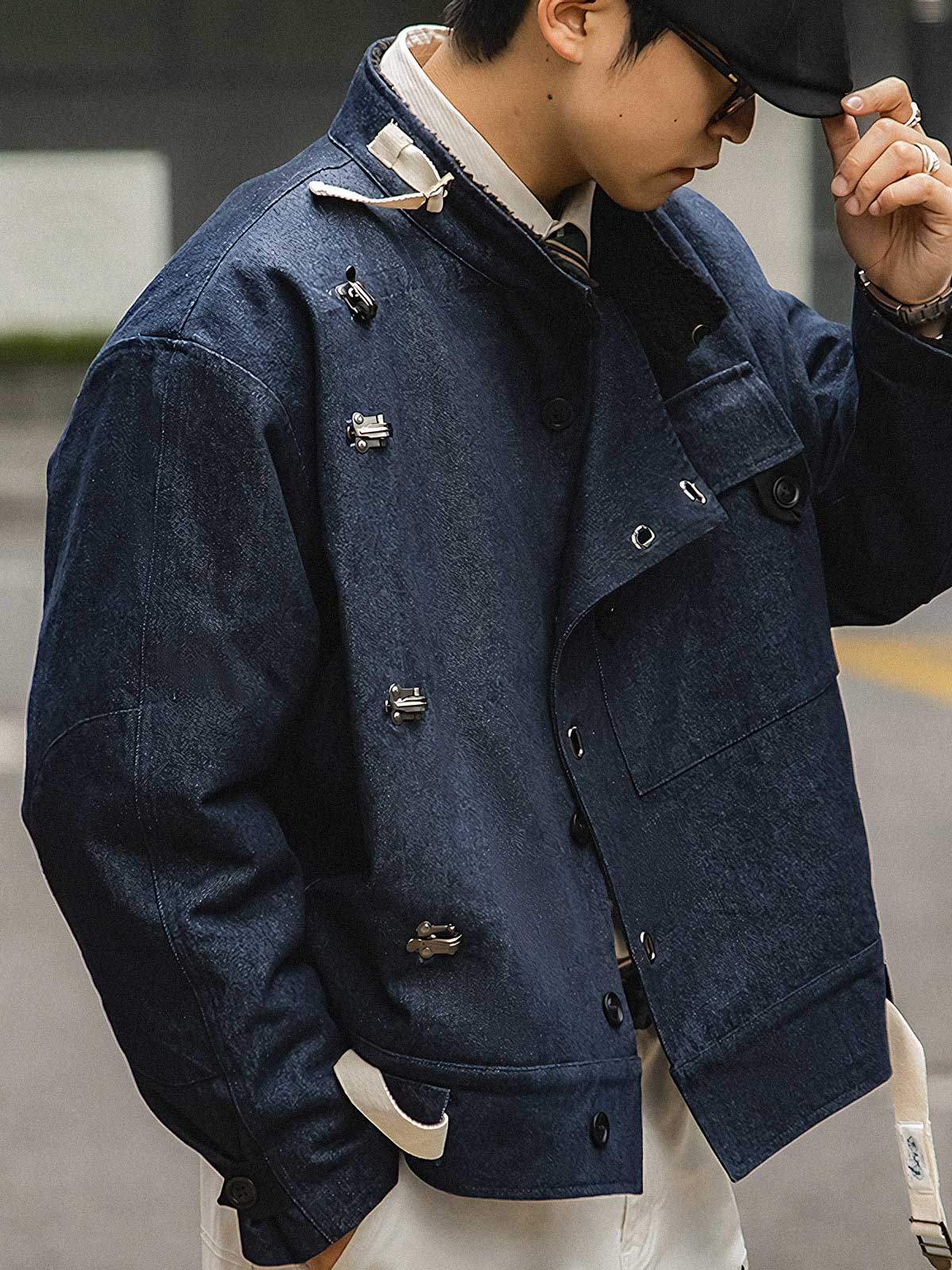 詳細画像
デッキフックとスウェードラベルのディテールクローズアップ。海軍スタイルのボタンとレトロなデザインがミリタリー感を際立たせる。
モデル画像
モデルが着用したレトロなバイカージャケットの冬のスタイル展示。デニムとワークブーツとの相性が抜群で、硬派な冬のコーディネートが完成。