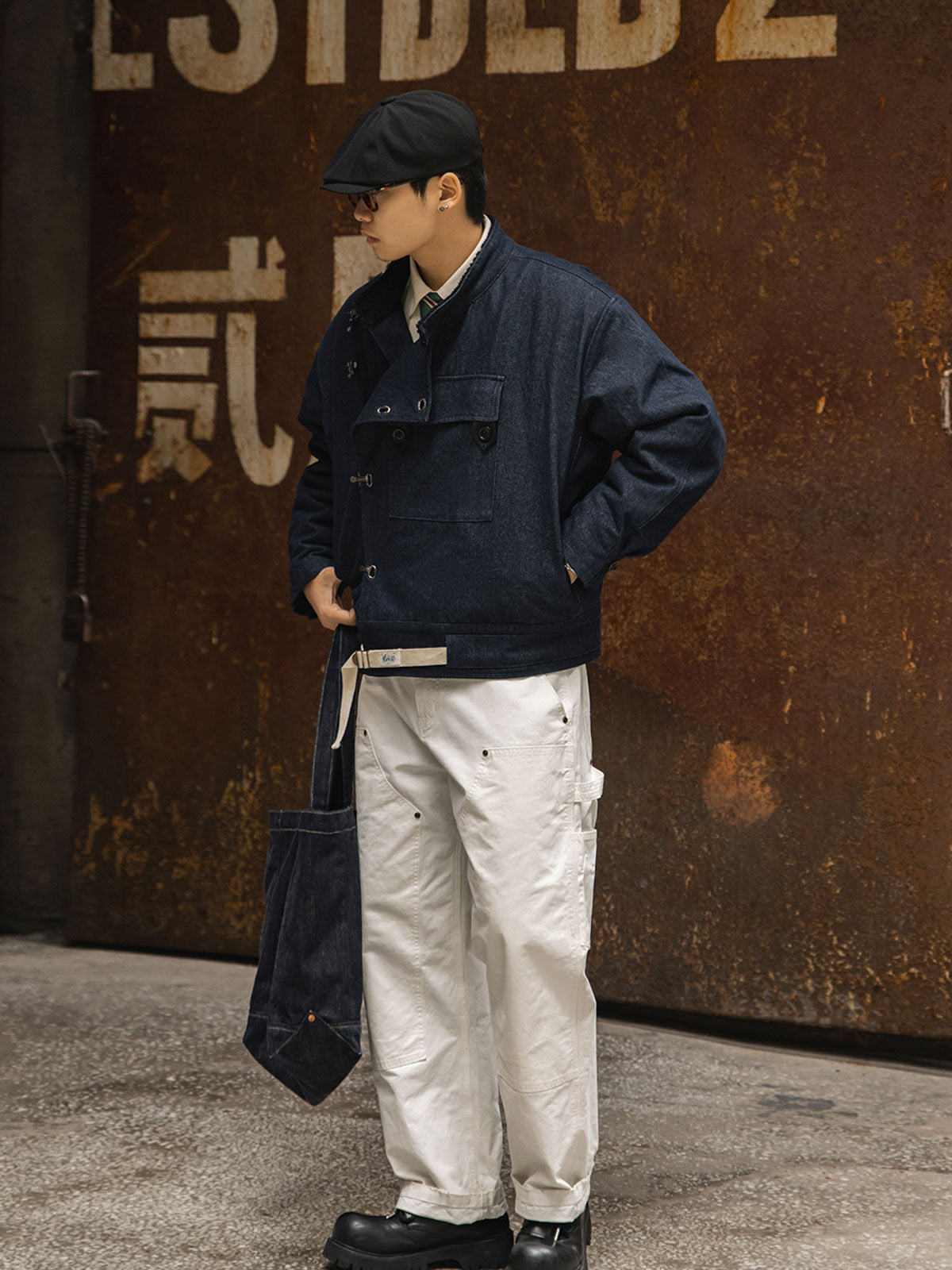 詳細画像
デッキフックとスウェードラベルのディテールクローズアップ。海軍スタイルのボタンとレトロなデザインがミリタリー感を際立たせる。
モデル画像
モデルが着用したレトロなバイカージャケットの冬のスタイル展示。デニムとワークブーツとの相性が抜群で、硬派な冬のコーディネートが完成。