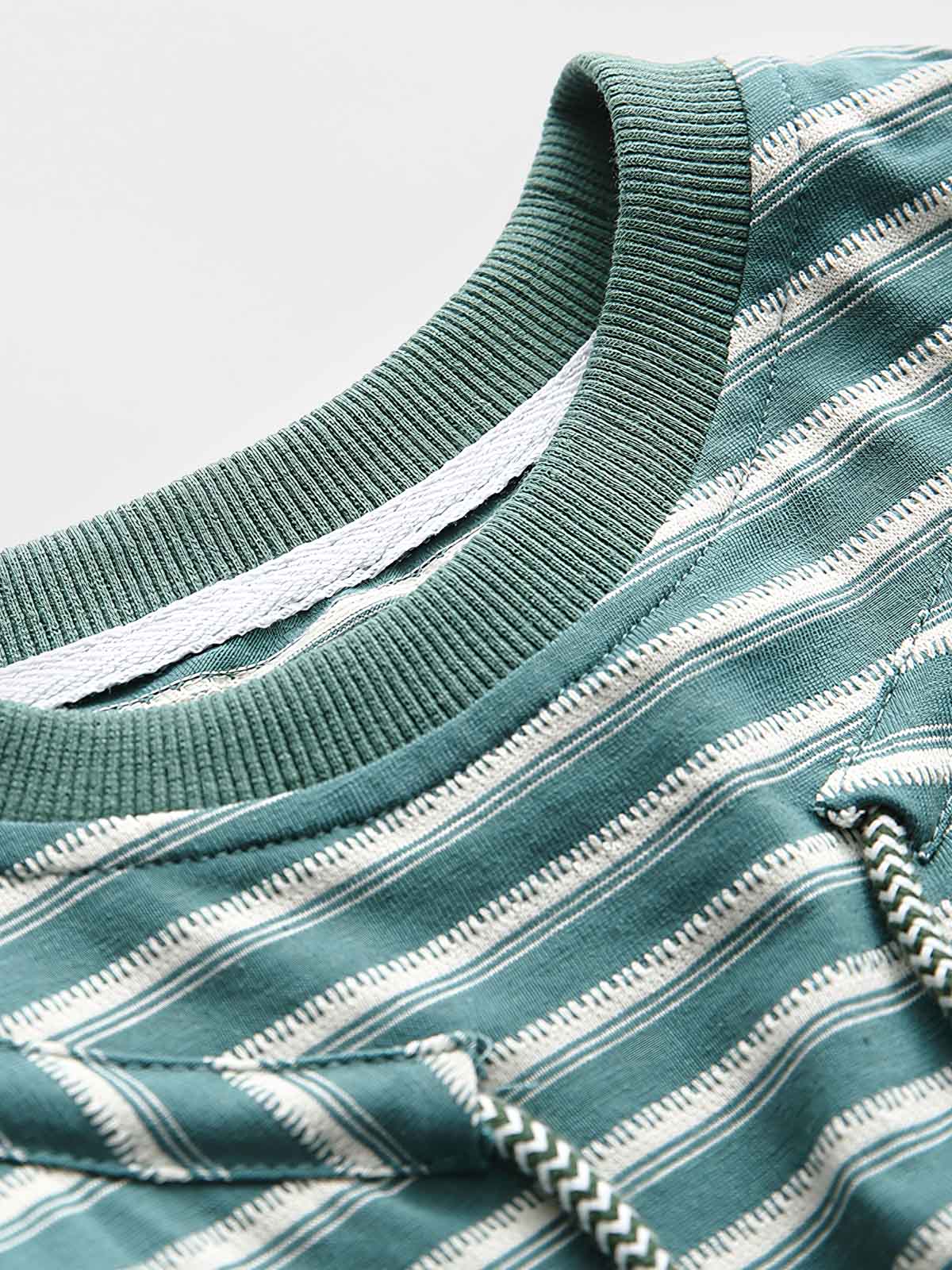 Tシャツの調節可能なドローストリング襟のクローズアップ。詳細なステッチとストライプパターンが特徴。