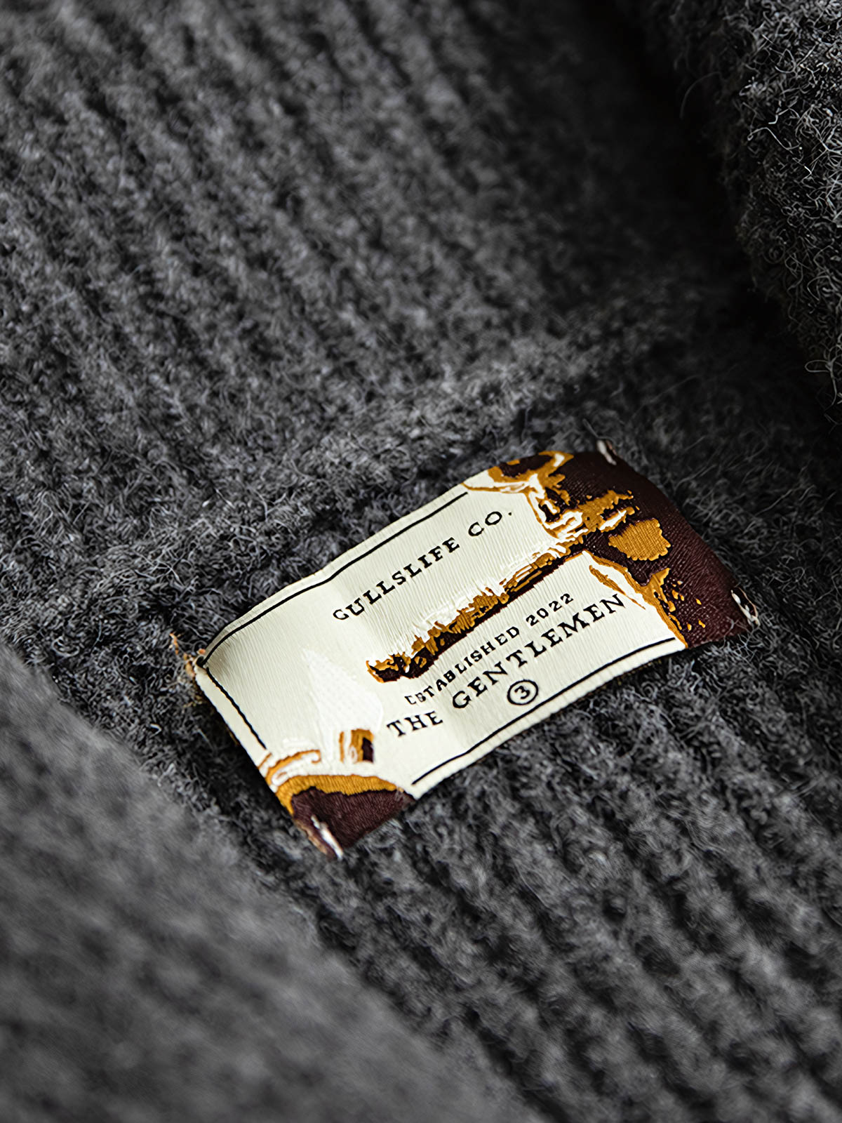 製品画像
加厚メリノウールを使用したニットカーディガンの全体展示。柔らかく暖かいメリノウール混紡素材を採用し、冬に最適な保温性と耐久性を兼ね備えた厚手デザインが特徴。
詳細画像
ニットカーディガンのリブ編みディテールとブランドカスタム「ジェントルマン」デザインを特写。型崩れしにくいリブ編み技術と高級感あふれるディテールが際立つクローズアップ画像。
