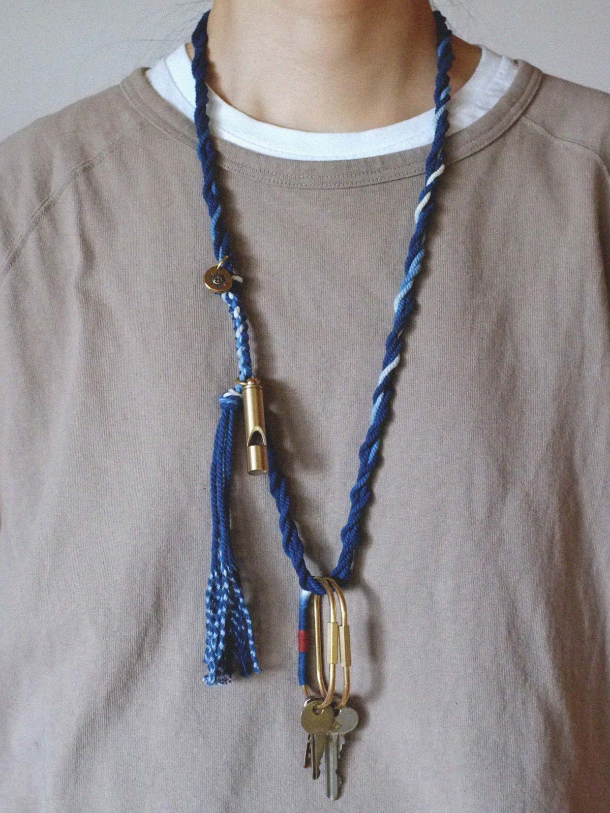 モデルがブルーダイブレードネックレスを着用し、金属製サバイバルホイッスルペンダントを示している。