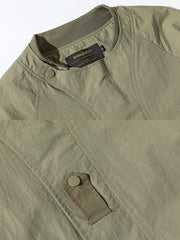 製品画像
「多機能ポケットデザインのアウトドアジャケット全体展示図。実用性とファッション性を兼ね備えたシルエットで、さまざまなシーンに対応可能な一着。」
詳細画像
「襟元のスナップボタンと斜めジッパーポケットのディテール特写。デザイン性と実用性を両立させたディテールが目を引きます。」