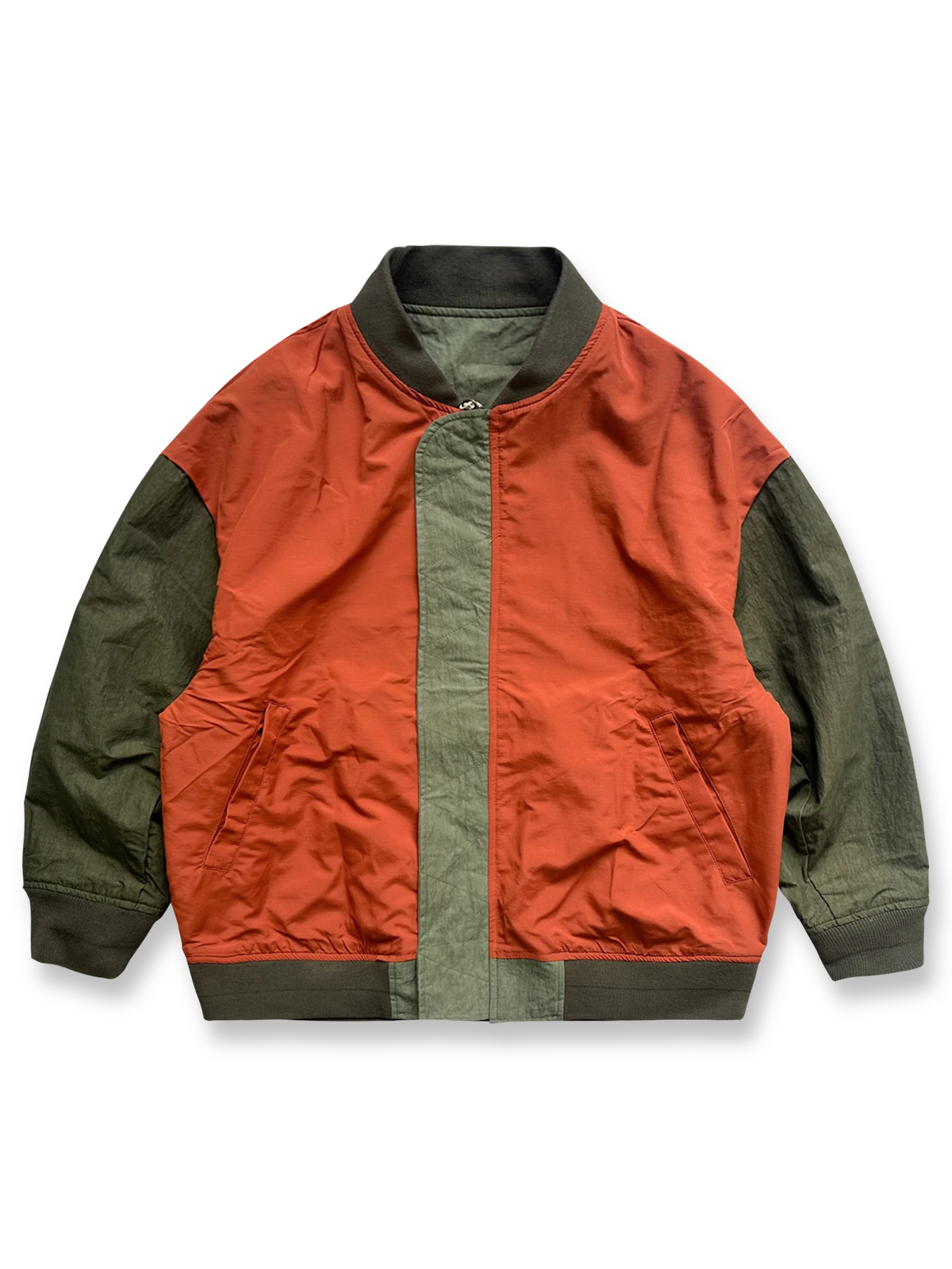 製品画像: リバーシブルジャケット(アーミーグリーン面)の全体展示図。表面にはアーミーグリーンのシンプルで落ち着いたデザイン、裏面には鮮やかなオレンジ色のアクセントが施されており、両面で異なるスタイルが楽しめる。
詳細画像: リバーシブルジャケットの表裏切り替えデザインとジッパー装飾ディテールの特写。防風防水機能素材で春秋の天候に対応し、実用性とスタイルを両立。