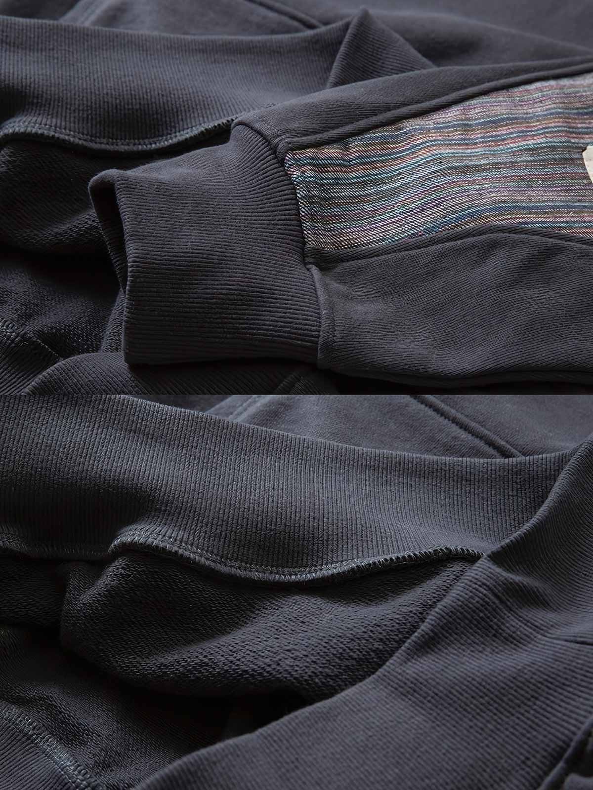 製品画像: ドロップ型肘パッチスウェット全体展示図。380gの厚手コットン素材を使用し、ヴィンテージ感とアート性が際立つデザイン。
詳細画像: 肘部分に施されたドロップ型パッチワークディテールの特写。コントラストの効いた配色とヴィンテージ風の装飾がポイント。