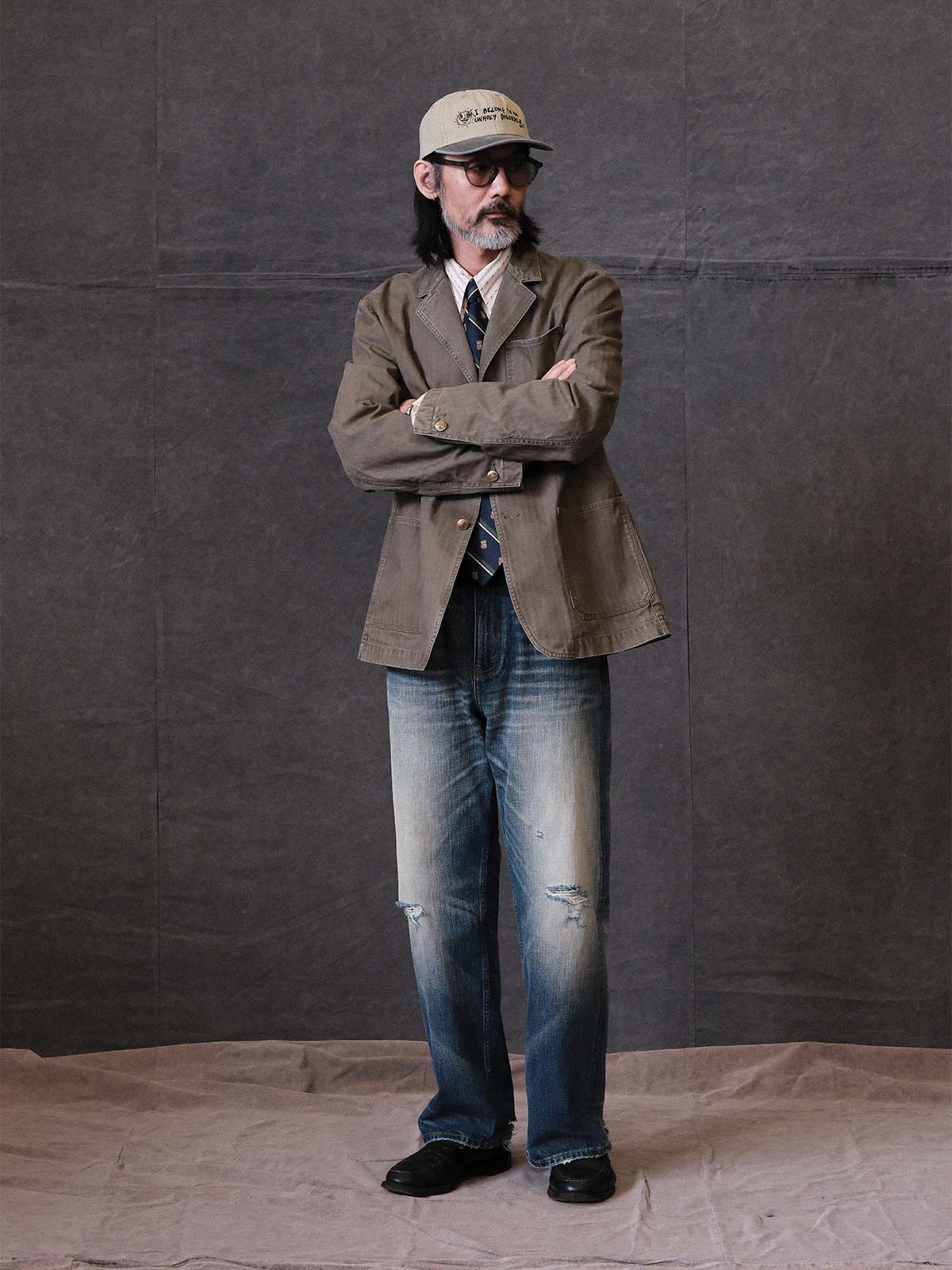 詳細画像: ウォッシュ加工されたヘリンボーン柄の生地とヴィンテージメタルボタンのディテール
モデル画像: ゆるやかなフィットでスタイリッシュなヴィンテージウォッシュジャケットの着用イメージ