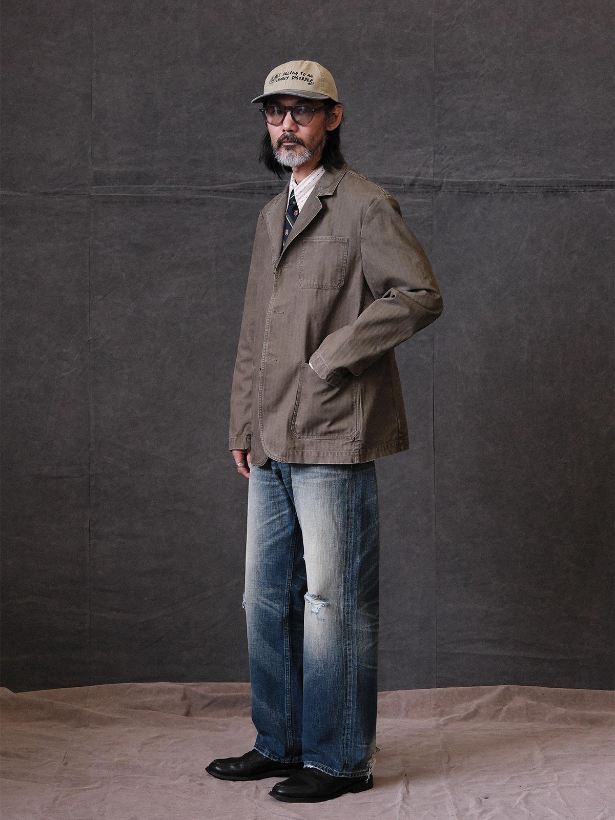 詳細画像: ウォッシュ加工されたヘリンボーン柄の生地とヴィンテージメタルボタンのディテール
モデル画像: ゆるやかなフィットでスタイリッシュなヴィンテージウォッシュジャケットの着用イメージ