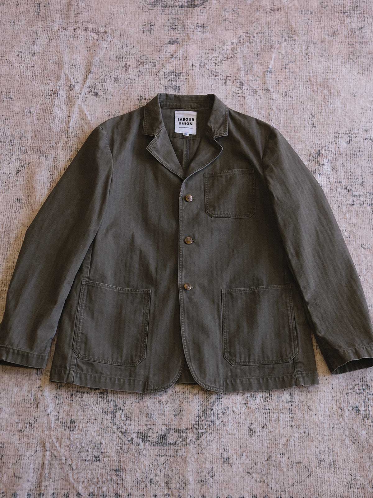 製品画像: ヴィンテージヘリンボーンウォッシュジャケットの全体画像、独特な時代感を持つデザイン
詳細画像: ウォッシュ加工されたヘリンボーン柄の生地とヴィンテージメタルボタンのディテール