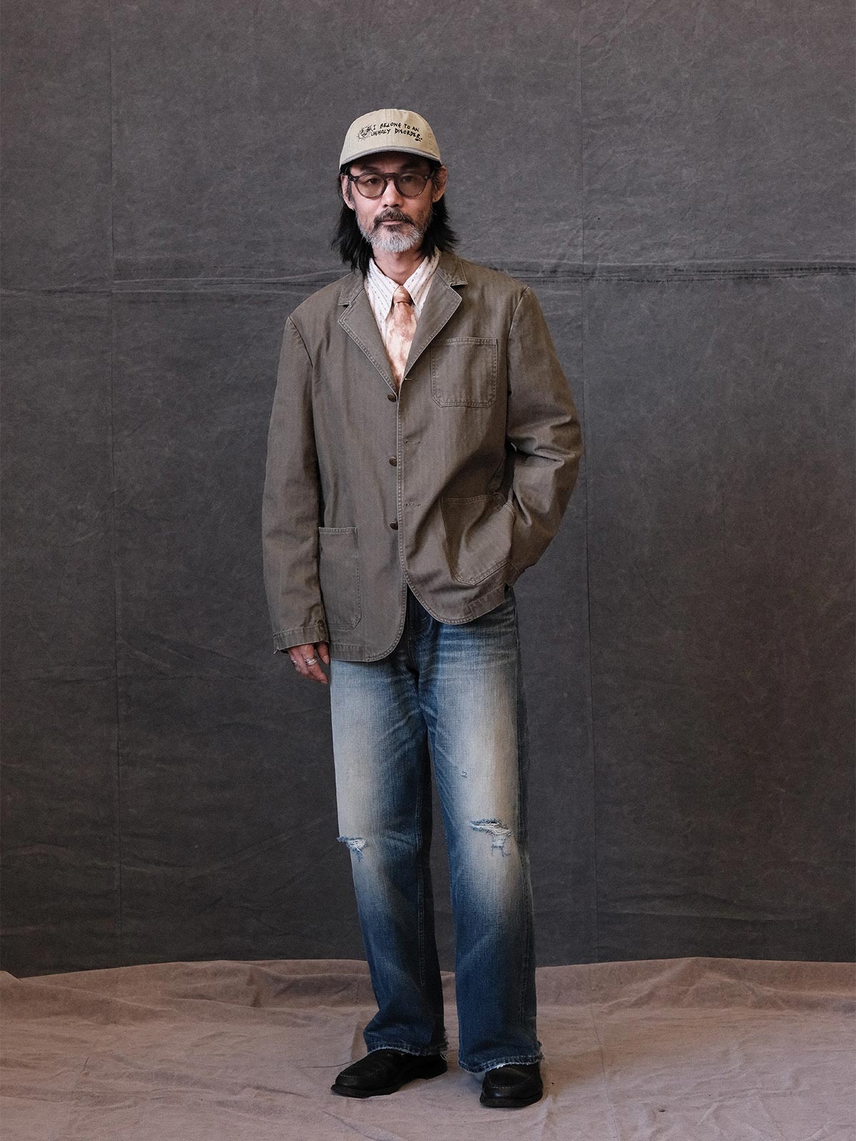 詳細画像: ウォッシュ加工されたヘリンボーン柄の生地とヴィンテージメタルボタンのディテール
モデル画像: ゆるやかなフィットでスタイリッシュなヴィンテージウォッシュジャケットの着用イメージ