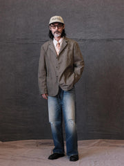 詳細画像: ウォッシュ加工されたヘリンボーン柄の生地とヴィンテージメタルボタンのディテール
モデル画像: ゆるやかなフィットでスタイリッシュなヴィンテージウォッシュジャケットの着用イメージ