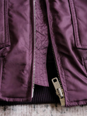 製品画像:
CWU-45Pフライトジャケットの全体展示。高密度ナイロン外層と厚手のキルティング綿を使用した、保温性と防風性に優れたクラシックなフライトジャケットの全体像。
詳細画像:
TALONメタルジッパーとマジックテープエンブレムのディテール。フラップポケットやリブ編みの袖口、裾など、ミリタリーウェア特有のデザインが強調された画像。