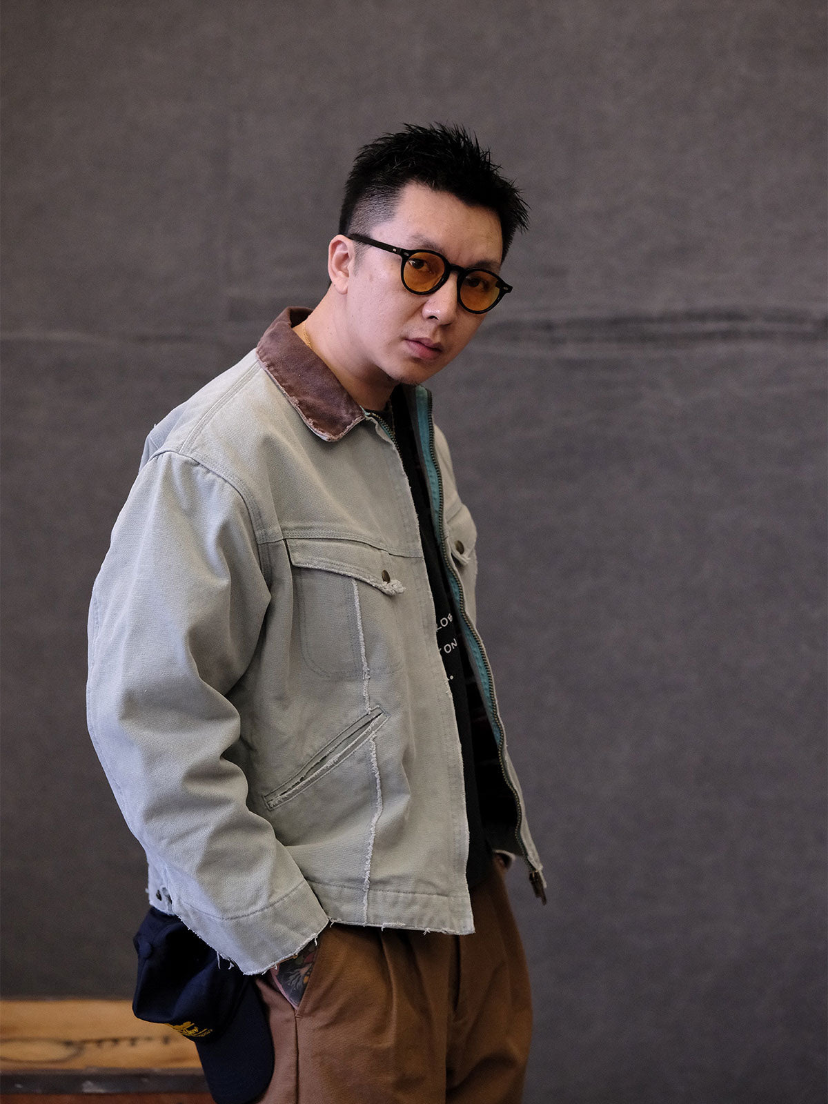 詳細画像:
TALONジッパー、スナップボタン、及び水洗い加工のディテール。多重水洗い加工と手作業のダメージ加工が施された、ヴィンテージ感が強調されたディテール。
モデル画像:
モデルがリバイバルキャンバスジャケットを着用し、カーゴパンツと合わせてアメリカンリバイバルスタイルを演出している画像。