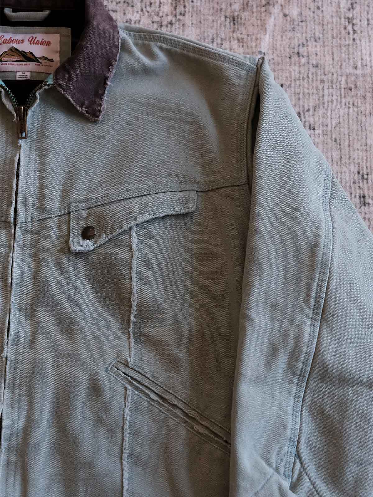 製品画像:
リバイバルダメージパッチワークキャンバスジャケット全体展示。15ozの定織キャンバスと日本製厚ウール裏地を使用し、ヴィンテージスタイルを引き立てるタフなキャンバスジャケットの全体像。
詳細画像:
TALONジッパー、スナップボタン、及び水洗い加工のディテール。多重水洗い加工と手作業のダメージ加工が施された、ヴィンテージ感が強調されたディテール。