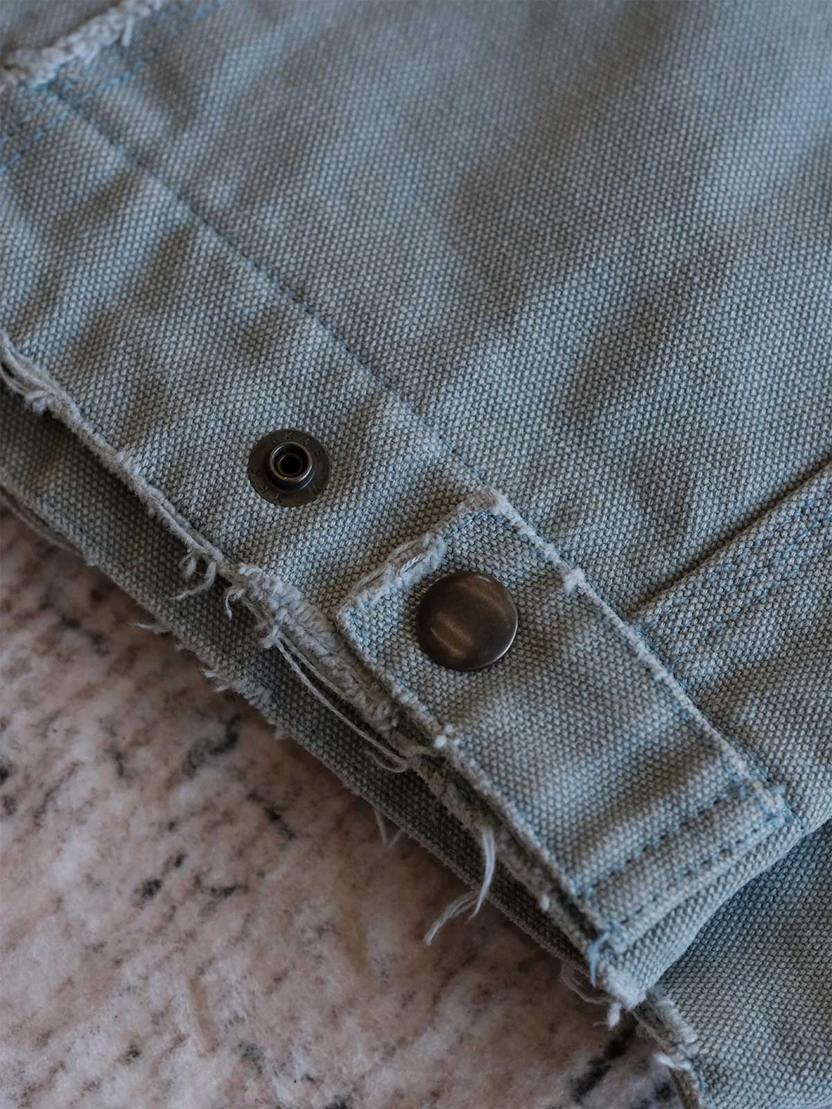 製品画像:
リバイバルダメージパッチワークキャンバスジャケット全体展示。15ozの定織キャンバスと日本製厚ウール裏地を使用し、ヴィンテージスタイルを引き立てるタフなキャンバスジャケットの全体像。
詳細画像:
TALONジッパー、スナップボタン、及び水洗い加工のディテール。多重水洗い加工と手作業のダメージ加工が施された、ヴィンテージ感が強調されたディテール。