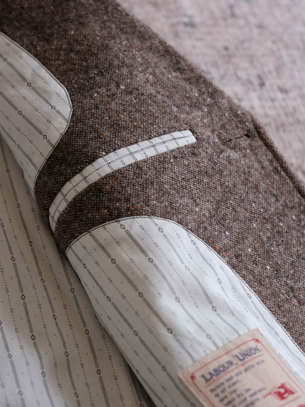 製品画像:
リバイバルカラードットウールツイードスーツジャケット全体展示。530gウールツイード生地とカラードットデザインで、1930年代のクラシックスタイルを現代的に再現したスーツジャケットの全体像。
詳細画像:
ツイード模様とカラードットデザインのディテール。リバイバル感を強調するために精緻なテクスチャーとカスタムボタンが施されたディテール。