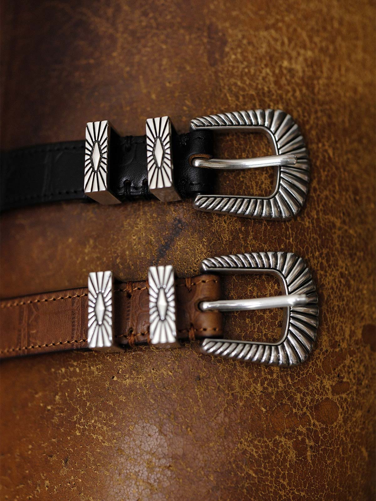 製品画像:
ヴィンテージキャバルリー インポートレザーベルト全景展示。アメリカンウェスタンスタイルにインスパイアされたインポートレザー素材のベルトで、タフでレトロなヴィンテージ感が表現された全体像。
詳細画像:
エッチング加工された真鍮バックルのディテール。精緻な彫刻が施された立体感のあるバックルが、ヴィンテージスタイルの魅力を引き立てるディテール。