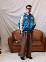 詳細画像:
精緻な刺繍と光沢サテン生地のディテール。大面積の刺繍デザインと鮮やかな色合いが、ジャケットに強い視覚的インパクトを与えるディテール。
モデル画像:
モデルがスカジョンジャケットを着用し、ジーンズやカーゴパンツと合わせて、クラシックなヴィンテージスタイルを披露している画像。