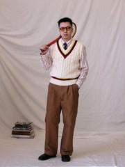 詳細画像:
ツイスト編みの編み目とカラーコンビネーションストライプのディテール。Vネックとストライプデザインが加える視覚的なレイヤード感を強調した画像。
モデル画像:
モデルがシャツと重ね着したVネック クリケットニットベストを着用し、英国風のアカデミックスタイルを演出している画像。