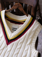 製品画像:
アカデミックスタイルVネック クリケットニットベストの全体展示。クラシックなツイスト編みとストライプデザインが特徴的な、100%ウール素材を使用したVネックデザインのニットベスト。
詳細画像:
ツイスト編みの編み目とカラーコンビネーションストライプのディテール。Vネックとストライプデザインが加える視覚的なレイヤード感を強調した画像。