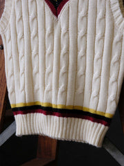 製品画像:
アカデミックスタイルVネック クリケットニットベストの全体展示。クラシックなツイスト編みとストライプデザインが特徴的な、100%ウール素材を使用したVネックデザインのニットベスト。
詳細画像:
ツイスト編みの編み目とカラーコンビネーションストライプのディテール。Vネックとストライプデザインが加える視覚的なレイヤード感を強調した画像。