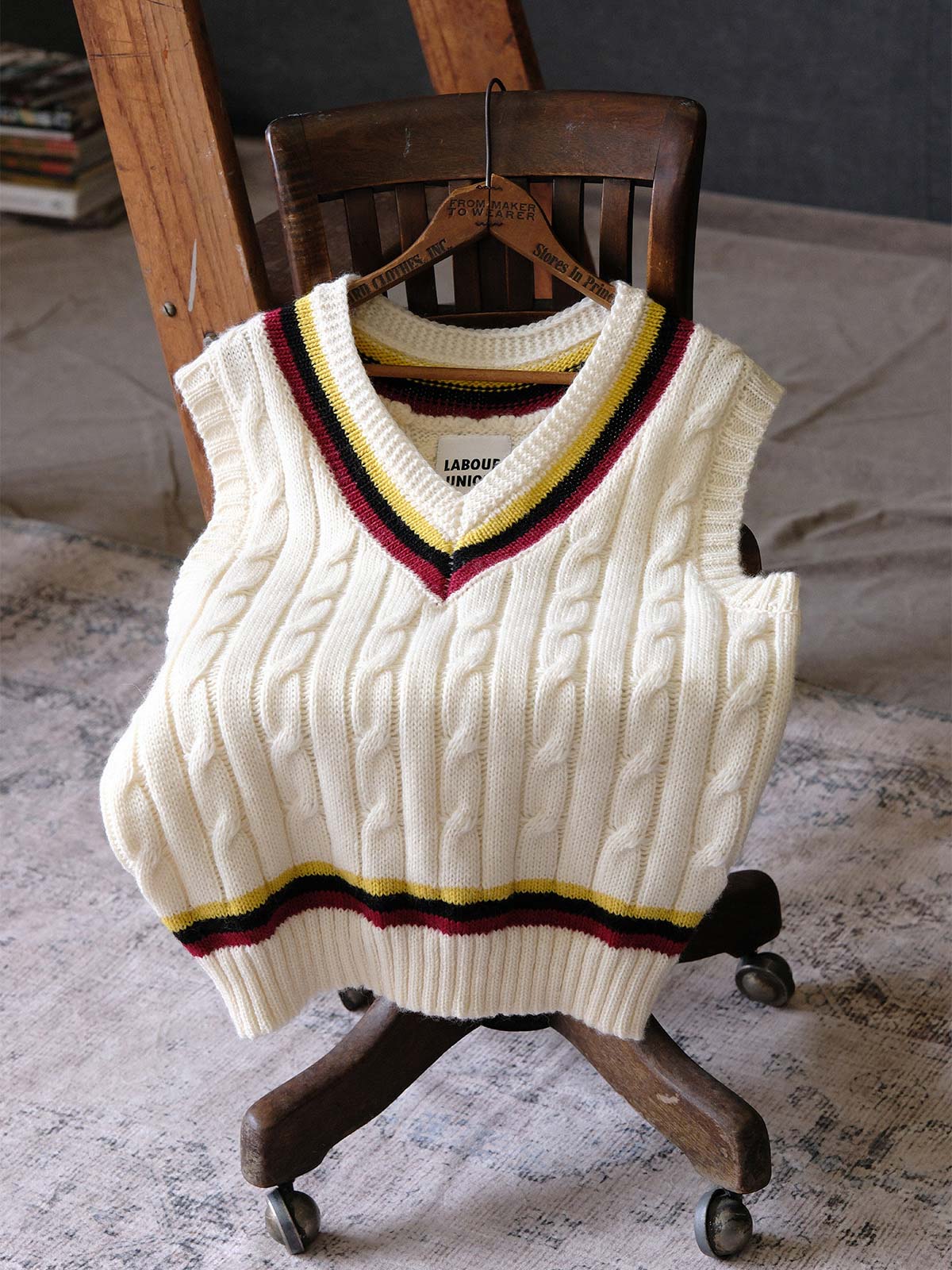 製品画像:
アカデミックスタイルVネック クリケットニットベストの全体展示。クラシックなツイスト編みとストライプデザインが特徴的な、100%ウール素材を使用したVネックデザインのニットベスト。
詳細画像:
ツイスト編みの編み目とカラーコンビネーションストライプのディテール。Vネックとストライプデザインが加える視覚的なレイヤード感を強調した画像。