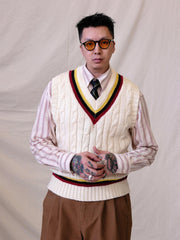 詳細画像:
ツイスト編みの編み目とカラーコンビネーションストライプのディテール。Vネックとストライプデザインが加える視覚的なレイヤード感を強調した画像。
モデル画像:
モデルがシャツと重ね着したVネック クリケットニットベストを着用し、英国風のアカデミックスタイルを演出している画像。