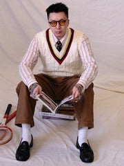 詳細画像:
ツイスト編みの編み目とカラーコンビネーションストライプのディテール。Vネックとストライプデザインが加える視覚的なレイヤード感を強調した画像。
モデル画像:
モデルがシャツと重ね着したVネック クリケットニットベストを着用し、英国風のアカデミックスタイルを演出している画像。