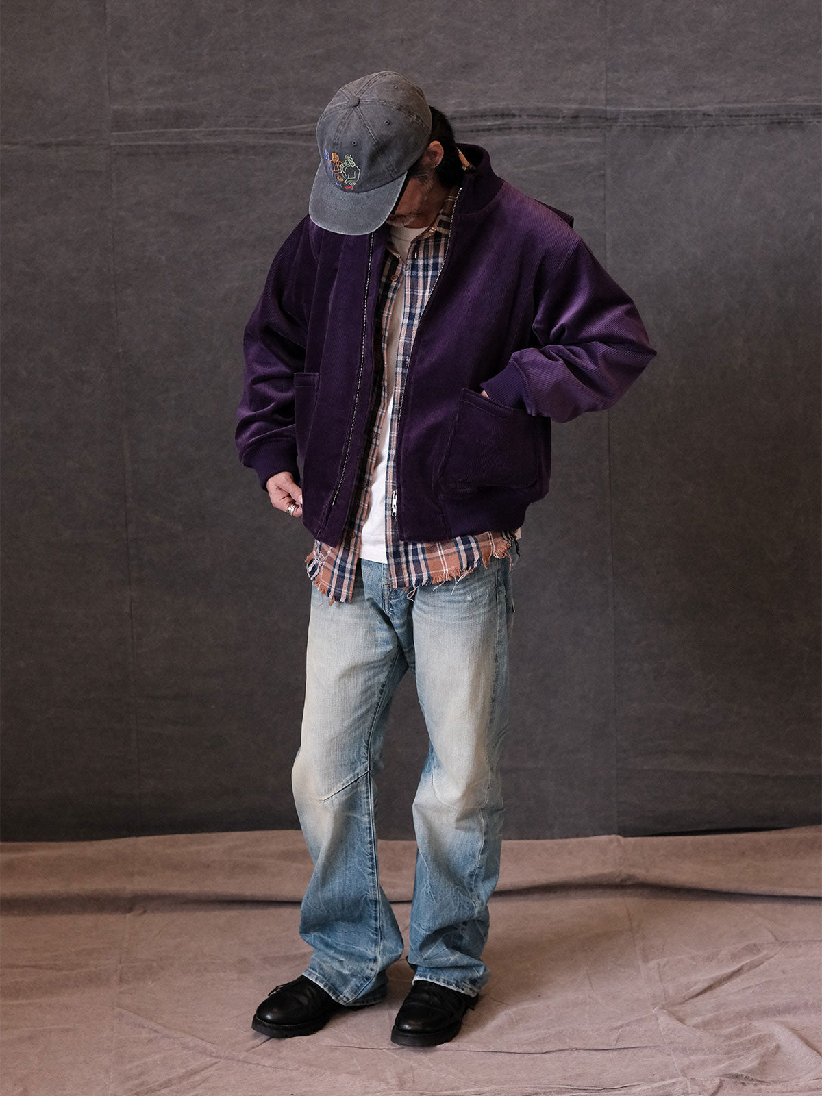 詳細画像:
リブ編みの襟、袖口、裾とプリーツデザインのディテール。寒風を防ぎ、自由な動きをサポートする機能的なデザインとミリタリー感が引き立ちます。
モデル画像:
モデルがコーデュロイ×ウール ミリタリージャケットを着用し、ミリタリースタイルのワークパンツと合わせてヴィンテージ軍旅風を披露。