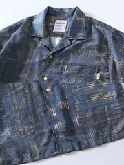 シャツのデニムプリントパターンと精緻なフロントボタンのクローズアップ。