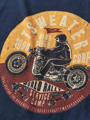 「Tシャツのフロントデザインのクローズアップ。ヴィンテージバイクのグラフィックとレトロな文字が目を引く。」