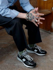 モデルがヴィンテージクラシックワイドスラックスを着用し、ストライプシャツと黒の革靴を合わせている。