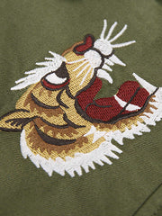 製品画像
リバーシブル仕様のトラ刺繍ワークシャツ全体デザイン。片面には胸元に精緻なトラ刺繍、もう片面には竹林に佇むトラのデザインが施された、オリエンタルデザインとミリタリースタイルが融合したシャツ
詳細画像
胸元に施されたトラ刺繍と銅製ボタンのディテール特写。蘇繍(ソシュウ)の伝統技法による繊細なステッチと、クラシックなミリタリーグリーンキャンバス素材の質感が特徴