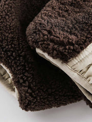 製品画像: リバーシブル シープスキン 中綿ジャケット。柔らかなシープスキンと耐久性のある織りナイロン素材を組み合わせた、多用途デザインの正面全体展示図。
詳細画像: バイカラーデザインと多機能ポケット、さらにハイネック仕様が特徴のリバーシブルジャケットのディテールクローズアップ。