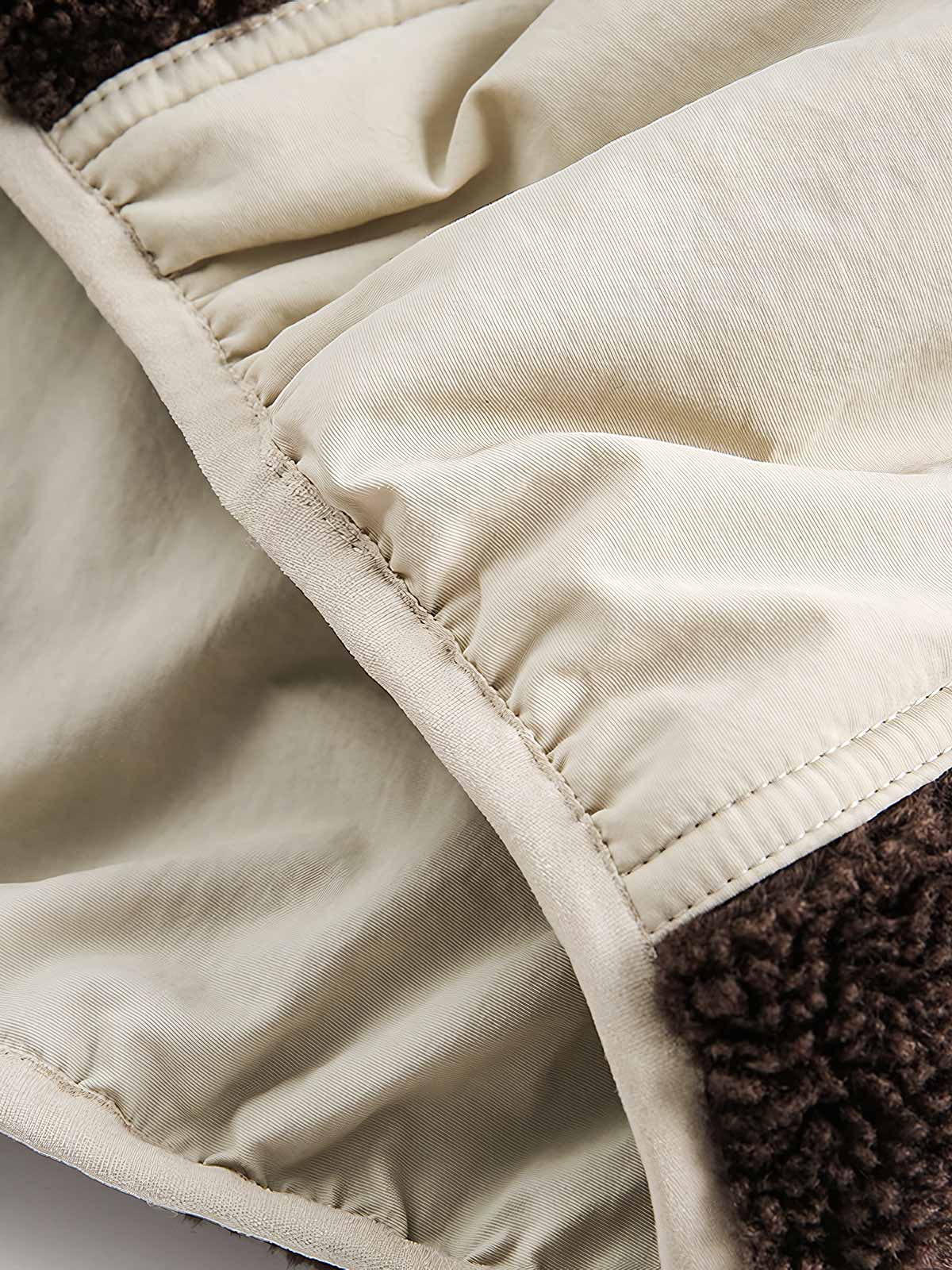 製品画像: リバーシブル シープスキン 中綿ジャケット。柔らかなシープスキンと耐久性のある織りナイロン素材を組み合わせた、多用途デザインの正面全体展示図。
詳細画像: バイカラーデザインと多機能ポケット、さらにハイネック仕様が特徴のリバーシブルジャケットのディテールクローズアップ。