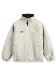 製品画像: リバーシブル シープスキン 中綿ジャケット。柔らかなシープスキンと耐久性のある織りナイロン素材を組み合わせた、多用途デザインの正面全体展示図。
詳細画像: バイカラーデザインと多機能ポケット、さらにハイネック仕様が特徴のリバーシブルジャケットのディテールクローズアップ。