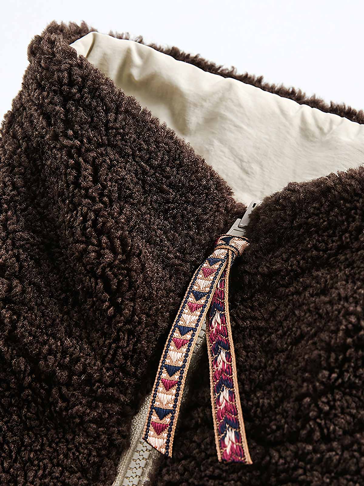 製品画像: リバーシブル シープスキン 中綿ジャケット。柔らかなシープスキンと耐久性のある織りナイロン素材を組み合わせた、多用途デザインの正面全体展示図。
詳細画像: バイカラーデザインと多機能ポケット、さらにハイネック仕様が特徴のリバーシブルジャケットのディテールクローズアップ。