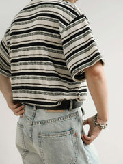 モデルがブラック&ホワイト・ストライプ・ショートスリーブTシャツを着用し、その全体的なスタイルとフィット感を示しています